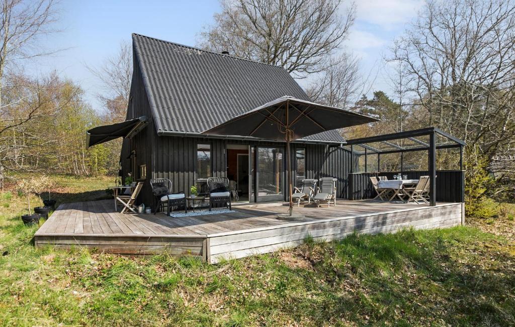 ein schwarzes Haus mit einer Terrasse mit einem Tisch und Stühlen in der Unterkunft 2 Bedroom Cozy Home In Tisvildeleje in Tisvildeleje