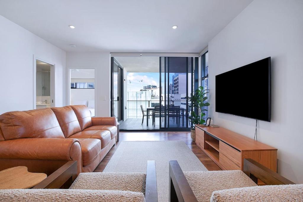 a living room with a couch and a flat screen tv at Regatta Hideaway - A Breezy Balcony Residence in Brisbane