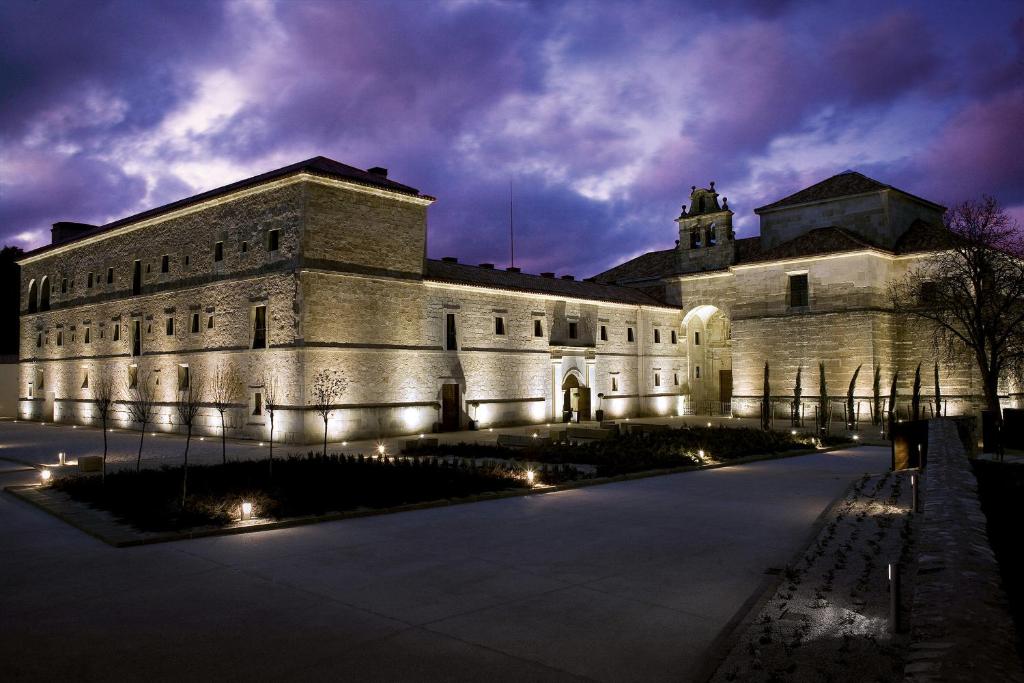 ein großes Steingebäude in der Nacht mit Lichtern in der Unterkunft Hospederia Convento San Francisco in Santo Domingo de Silos