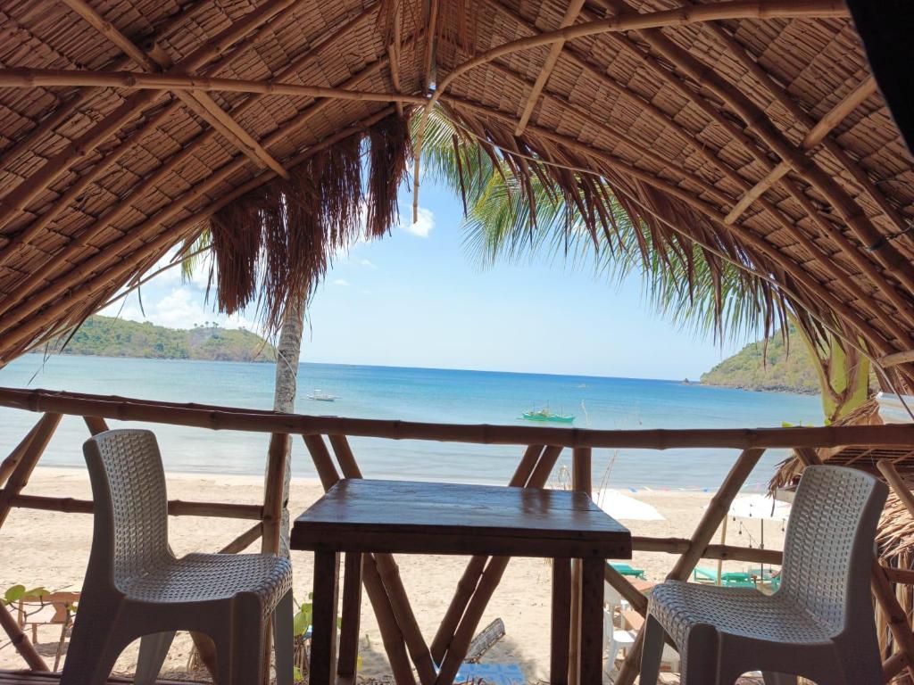 uma mesa e cadeiras numa praia com o oceano em 8 Star Paradise em Locaroc