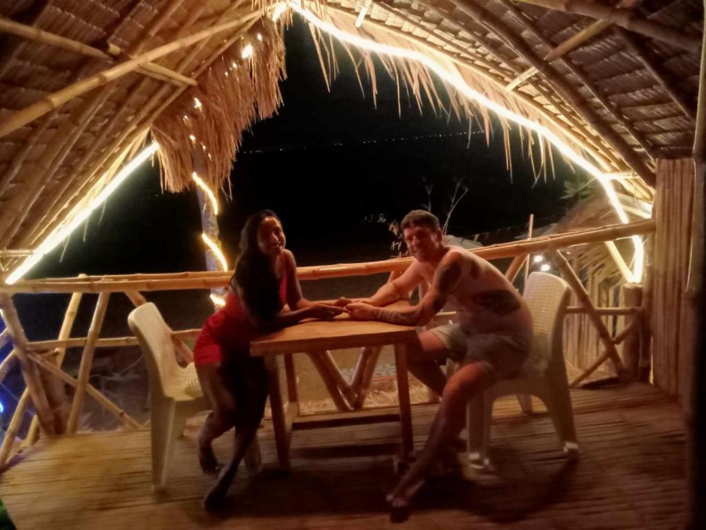 dos personas sentadas en una mesa de picnic en una cabaña en 8 Star Paradise en Locaroc