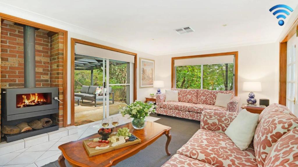 a living room with a couch and a fireplace at Alba Gardens in Bundanoon
