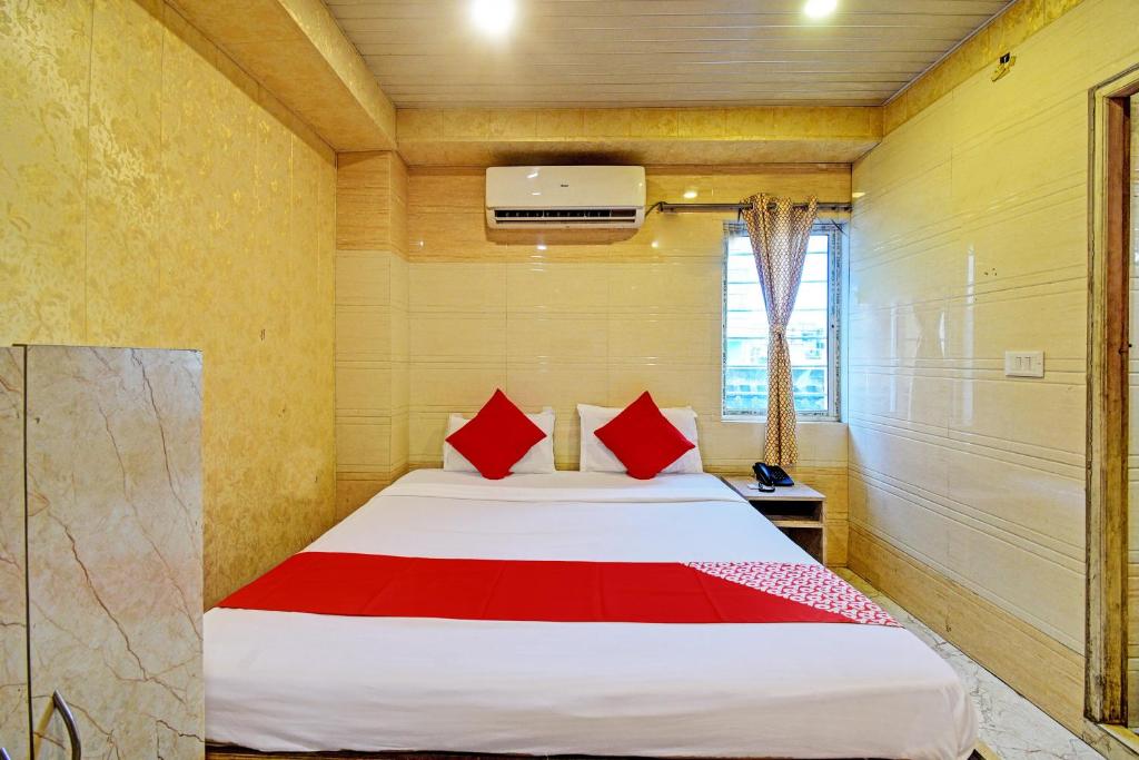 ein Schlafzimmer mit einem Bett mit roten Kissen in der Unterkunft Hotel Royal Inn in Kalkutta