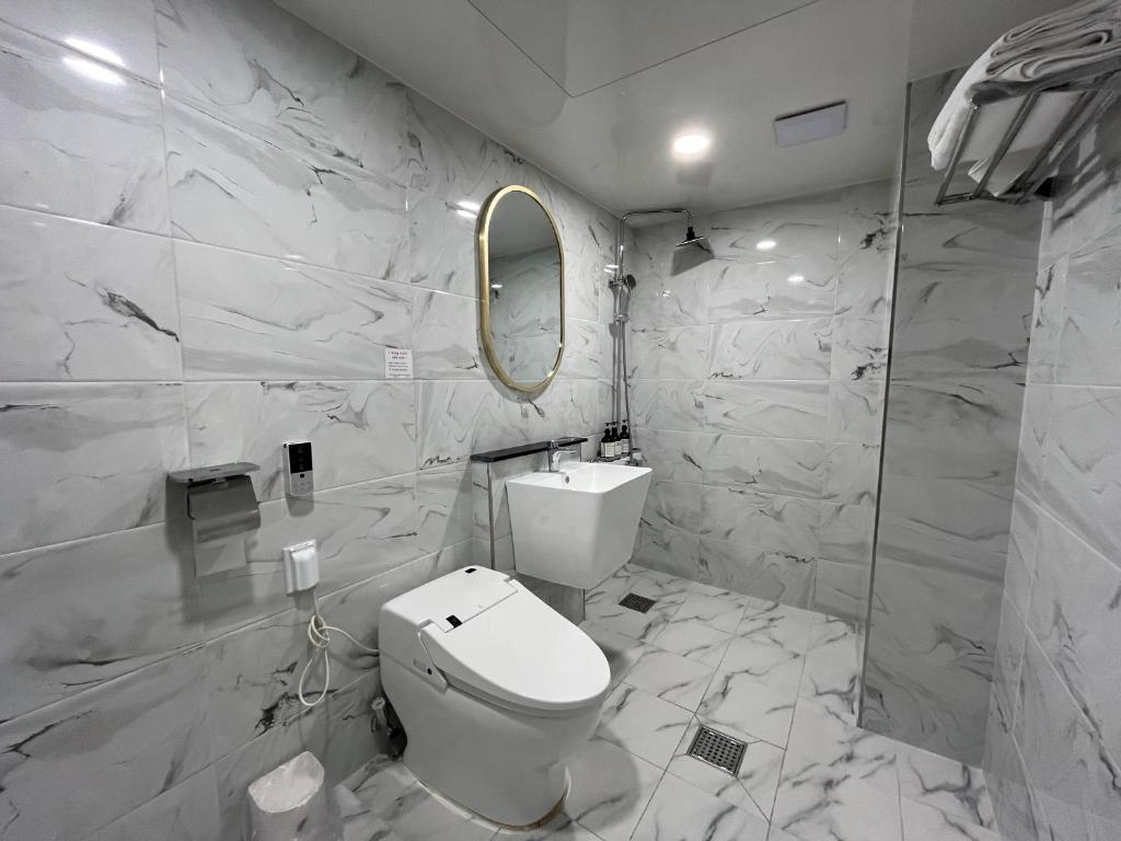 ein weißes Bad mit einem WC und einem Spiegel in der Unterkunft Hotel Gate in Incheon