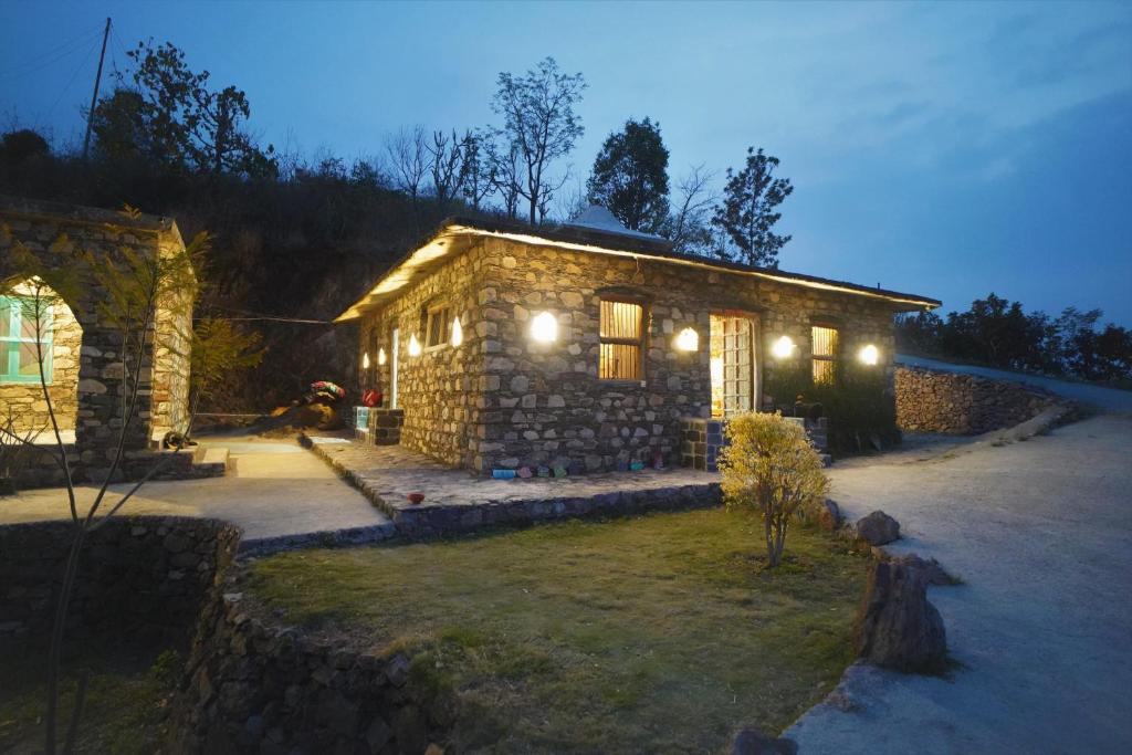 una casa de piedra con luces en el lateral. en Dirghayu Bhava Retreat, en Dehradun