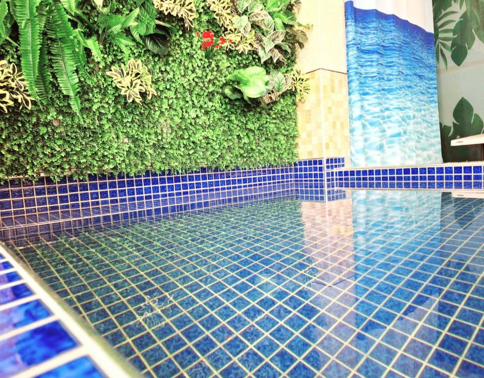 a swimming pool with blue tiles and a green wall at Have FUN villa in Hengchun South Gate