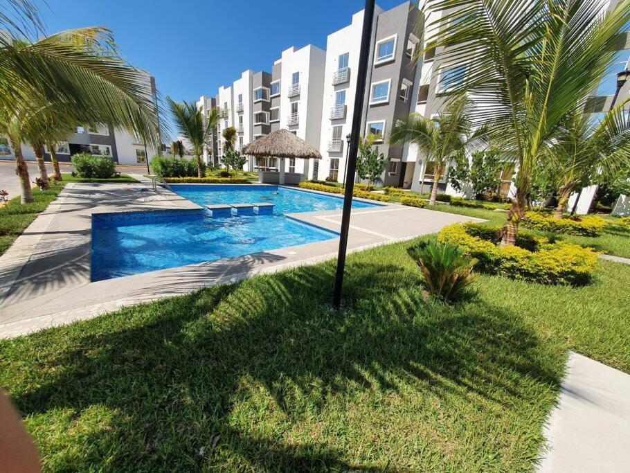 ein Swimmingpool vor einem Gebäude mit Palmen in der Unterkunft Departamento con Alberca in Valente Díaz y La Loma