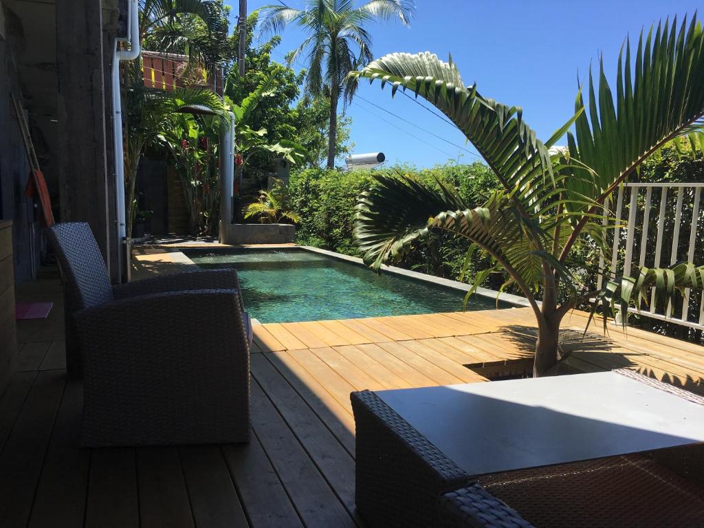 a swimming pool with a table and chairs on a deck at Manapany loft in Saint-Joseph