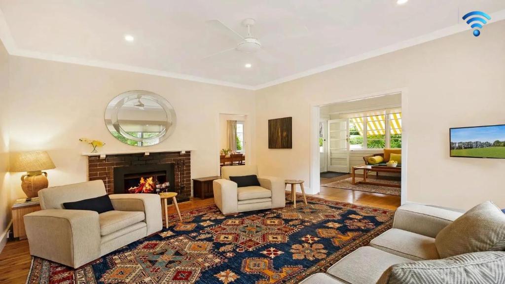 a living room with two chairs and a fireplace at Canary Cottage in Bowral
