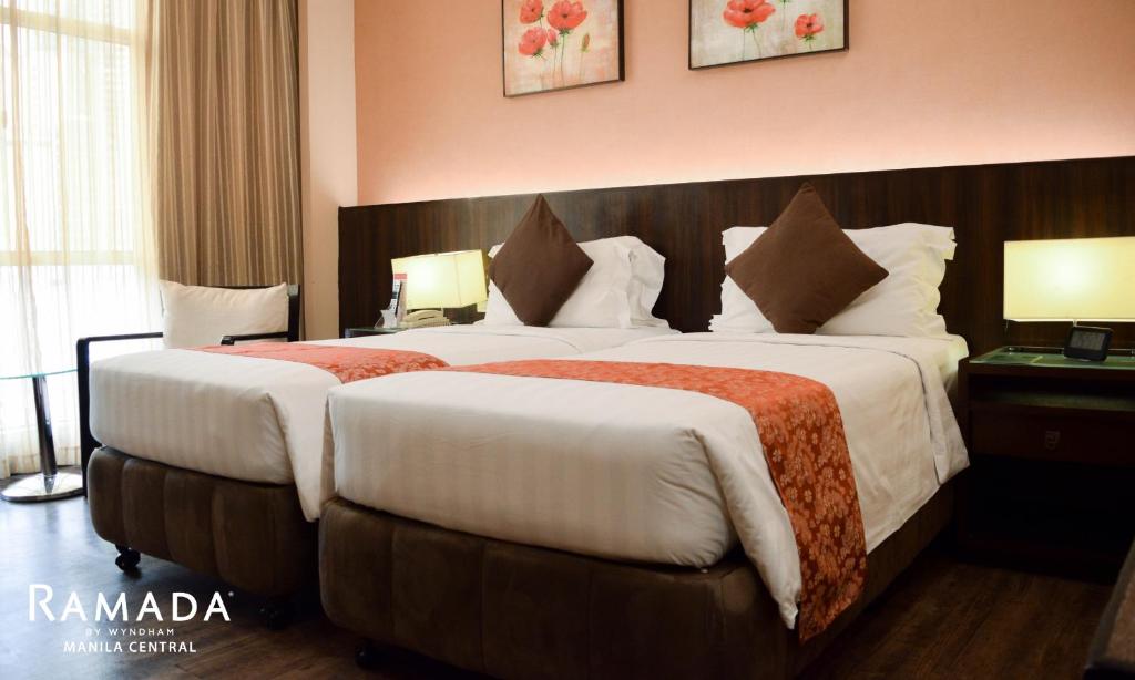 a hotel room with two beds and two lamps at Ramada by Wyndham Manila Central in Manila