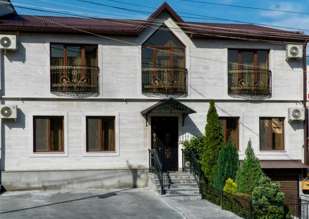 uma casa branca com uma porta preta e varanda em Hotel - Yerevan Retreat & Inn em Yerevan