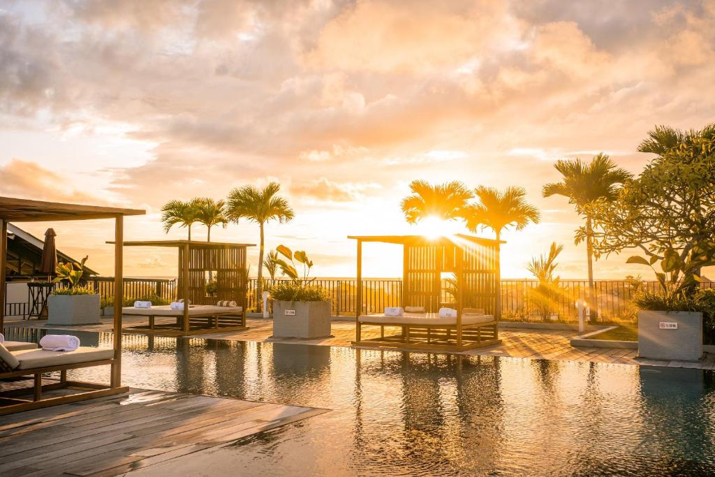 ein Resort mit einem Pool und Palmen in der Unterkunft Cross Paasha Bali Seminyak in Seminyak
