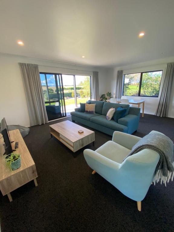 a living room with a blue couch and a table at Soul Sanctuary, with outdoor bath in Raglan