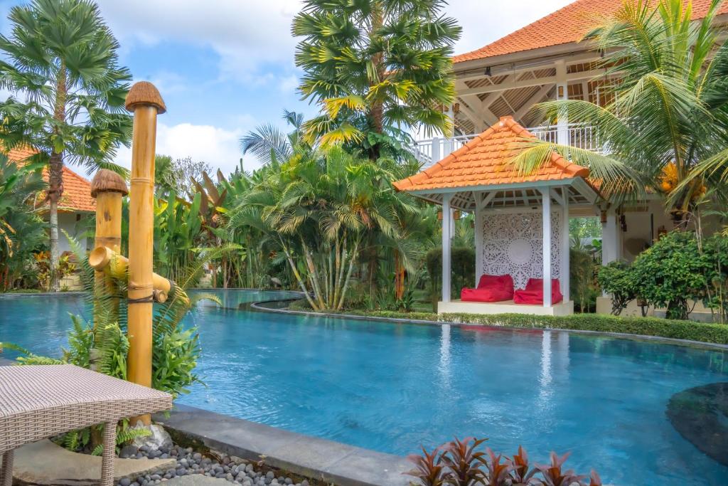 a swimming pool in front of a house with a gazebo at Tulus Hati Ubud Retreat in Ubud