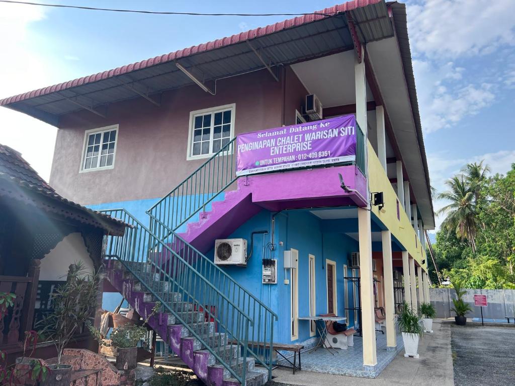 OYO 90967 Homestay Chalet Warisan Siti في كامبونغ بادانغ ماسير: مبنى ملون مع علامة أرجوانية عليه