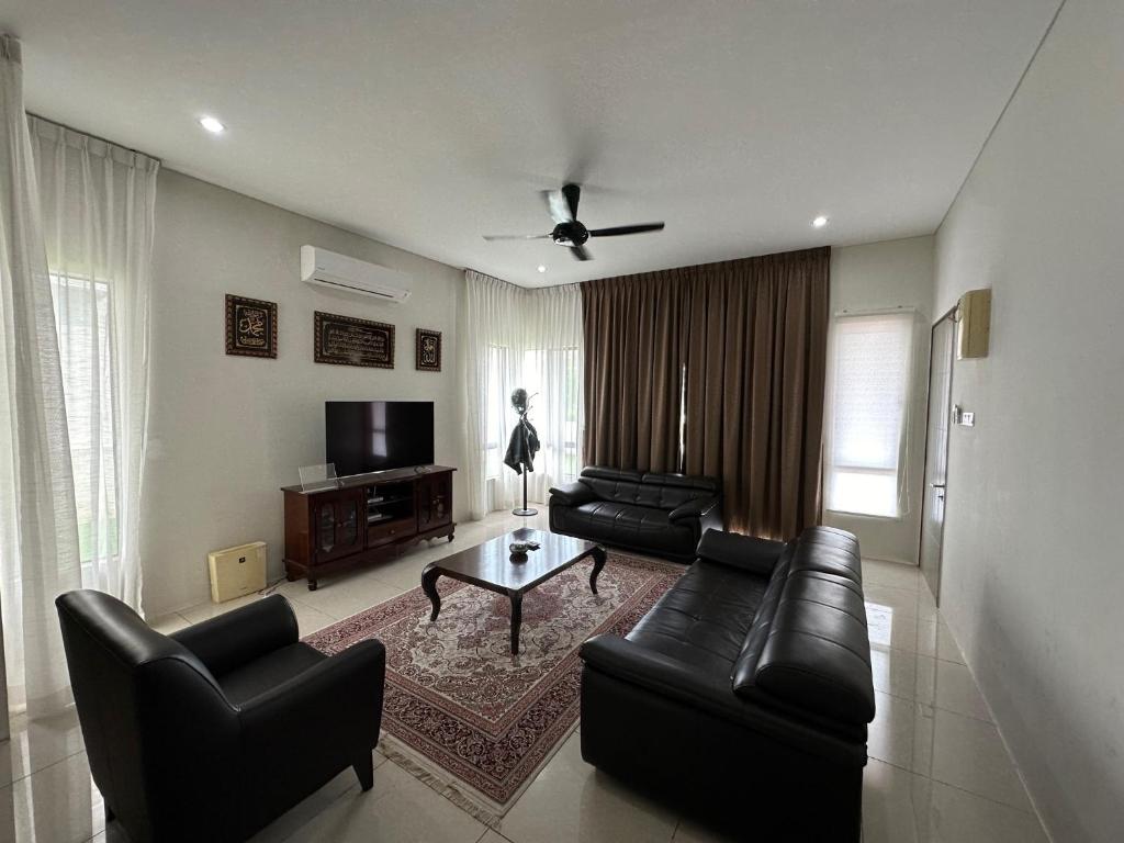 a living room with black leather furniture and a flat screen tv at Balqish House in Seremban