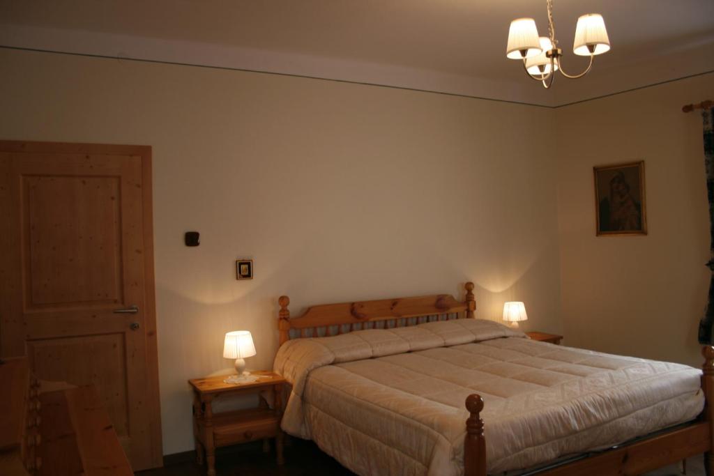 sypialnia z łóżkiem i 2 lampkami na stołach w obiekcie Casa Basilio w mieście Predazzo