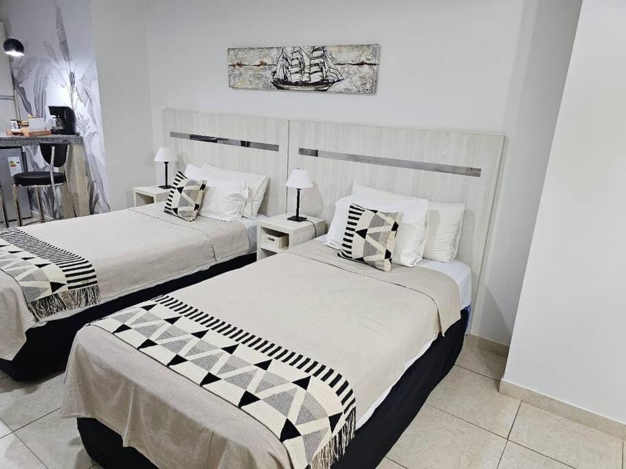 two beds in a room with white walls at Diseño y confort Monoambiente a pasos del Río! in Santa Fe