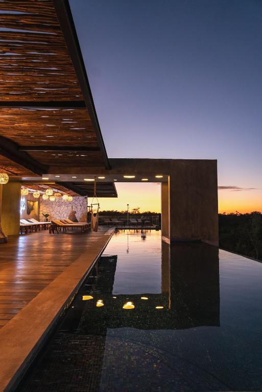 a swimming pool in the middle of a building with the sunset at Xambé in Tulum