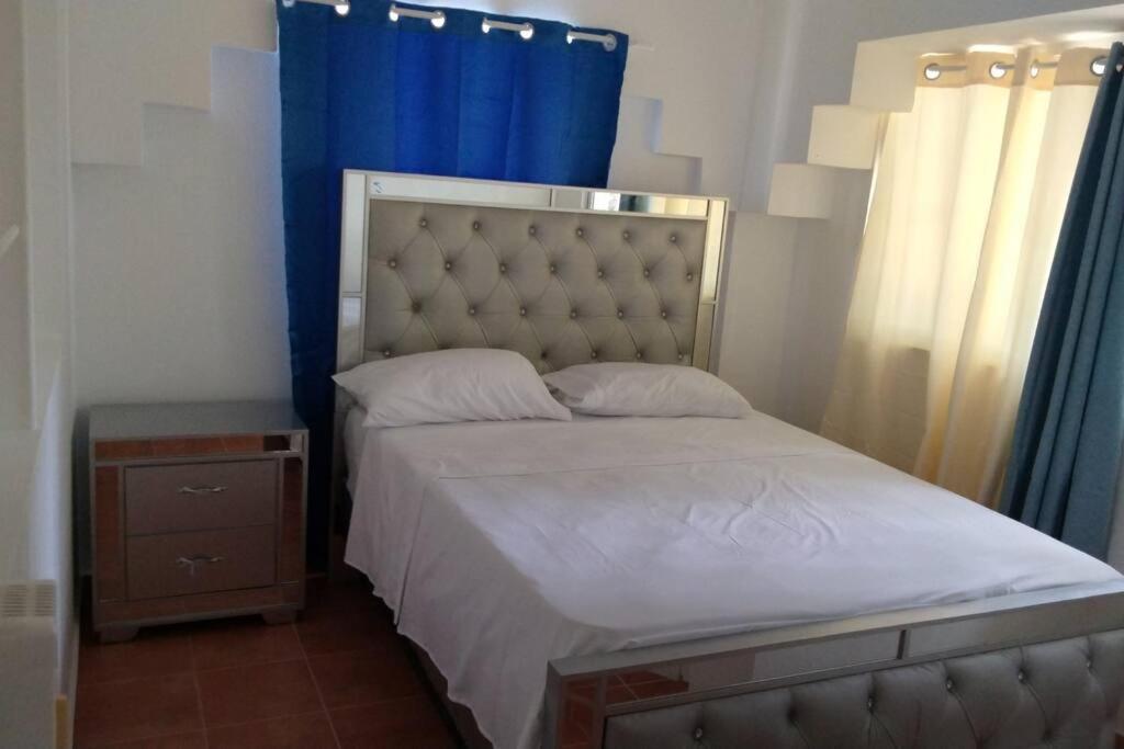 a bedroom with a large bed with a blue curtain at tropicana sur apt221 in Sosúa