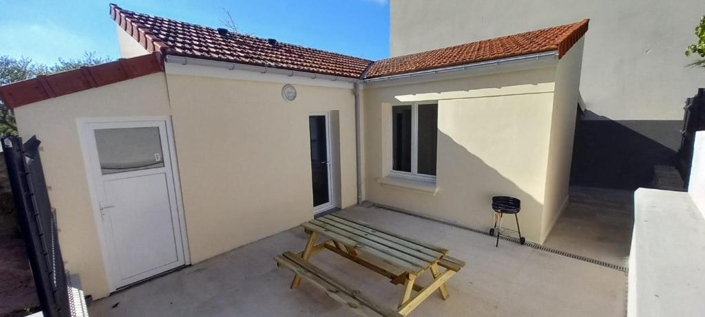 un banco sentado en un patio junto a un edificio en La maisonnette cherbourgeoise, en Cherbourg-en-Cotentin