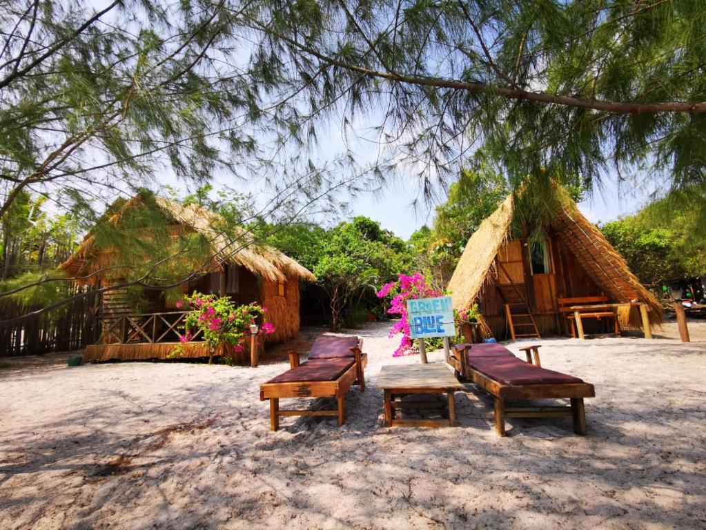 a group of benches sitting in front of some huts at GreenBlue Beach Bungalows in Koh Rong Sanloem