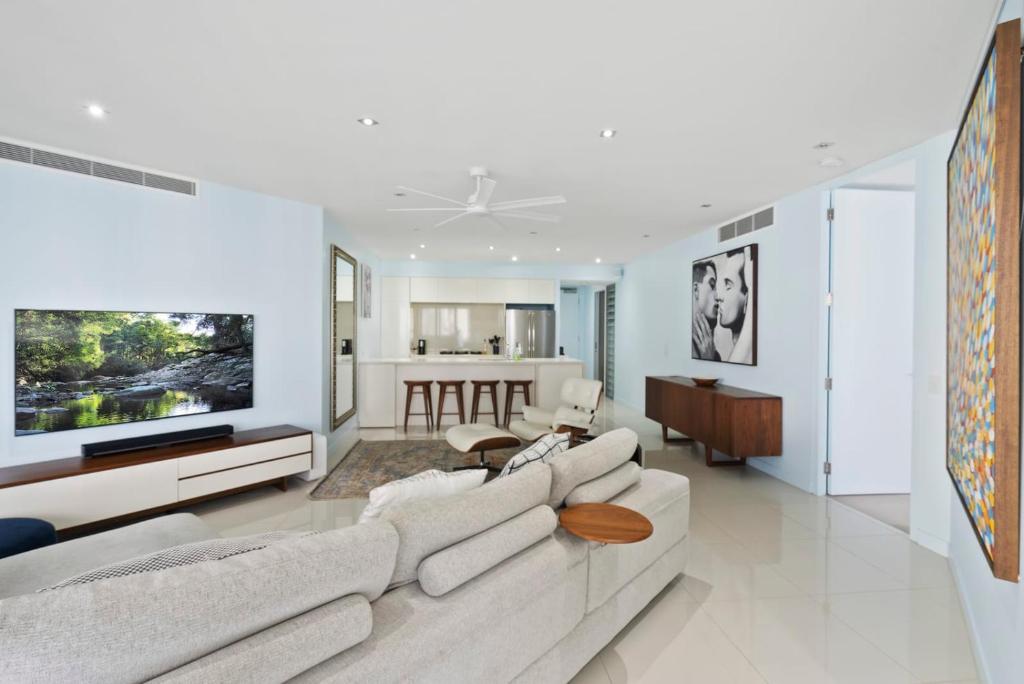 a living room with a white couch and a tv at Experience Brisbane in Style Spacious 3 BR Retreat with Parking in West End in Brisbane