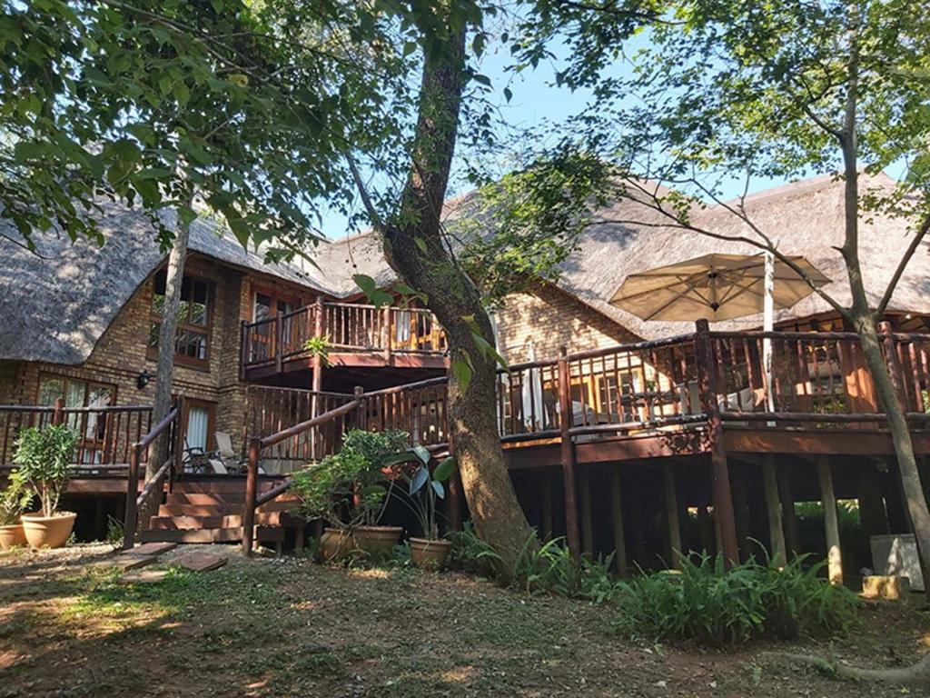 a large house with a deck and a tree at Dreamy 3 bedroom villa on the edge of the Sabie River in Kruger Park Lodge in Hazyview