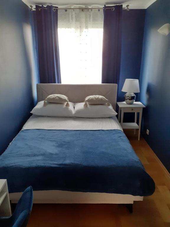 Schlafzimmer mit einem Bett mit blauen Wänden und einem Fenster in der Unterkunft GREEN AP Nalkowskich in Lublin