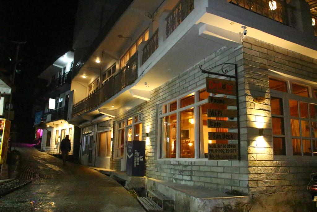 a person walking down a street next to a building at night at Drifters Inn - The Hidden Tribe in Manāli