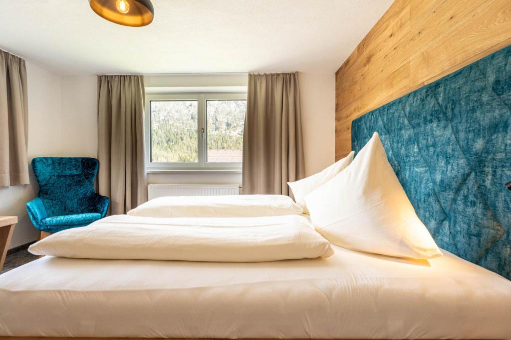 Habitación de hotel con cama y silla azul en Maurig Appartements, en Elbigenalp