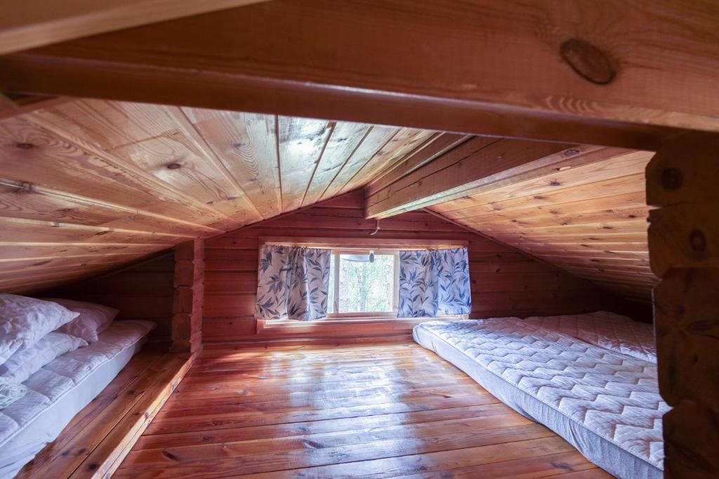 an attic room with two beds and a window at Pinetree Cottages Log cabin in Pyhäranta