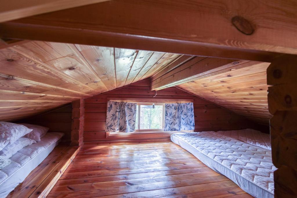 een zolderkamer met 2 bedden en een raam bij Pinetree Cottages Log cabin in Pyhäranta