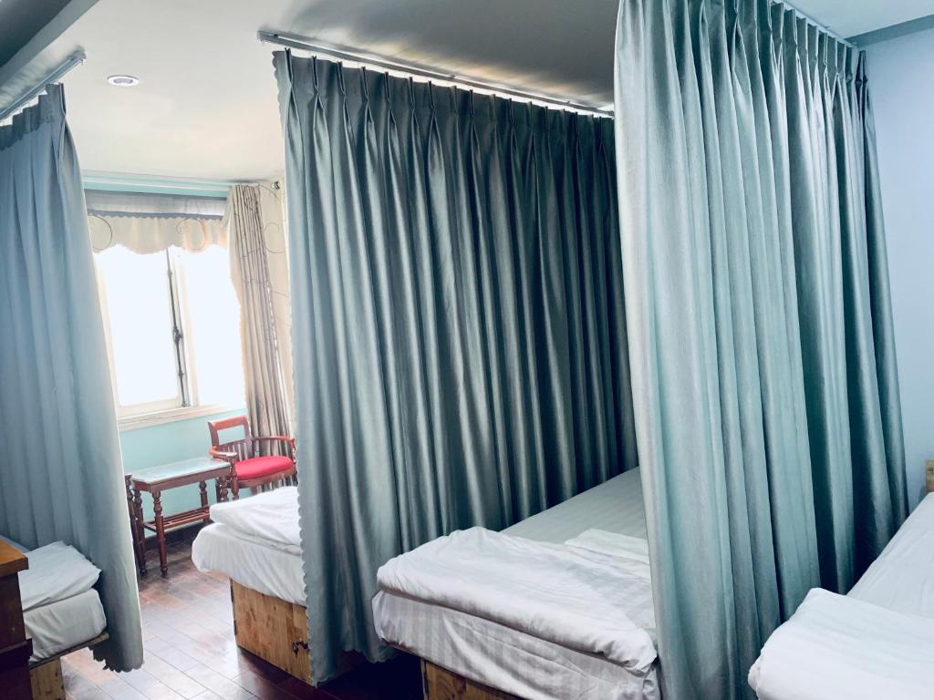 a bedroom with two beds with curtains and a window at Central Beach Hotel in Da Nang