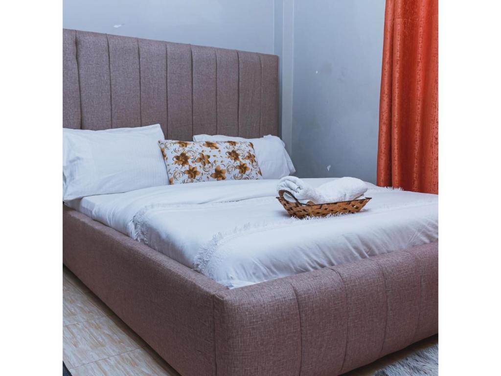- un lit avec des draps blancs et un panier dans l'établissement CH Two Bedroom Apartment Kisii, à Kisii
