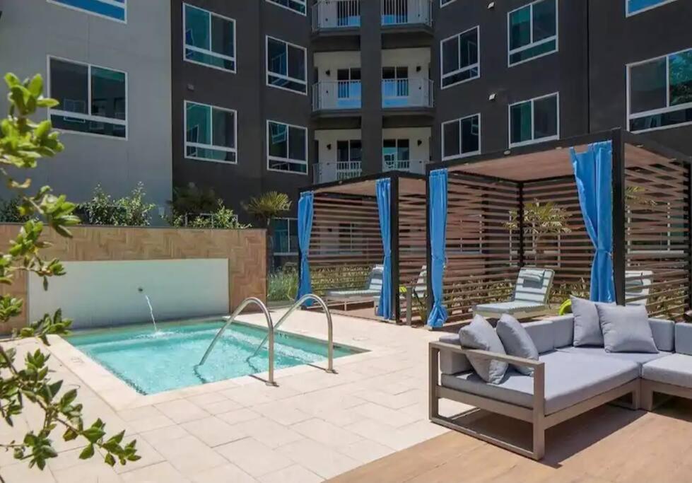 um pátio com um sofá e uma piscina em frente a um edifício em 8 minutes to Disneyland Sleeps 7 with 5 Beds 2 Bathrooms em Anaheim