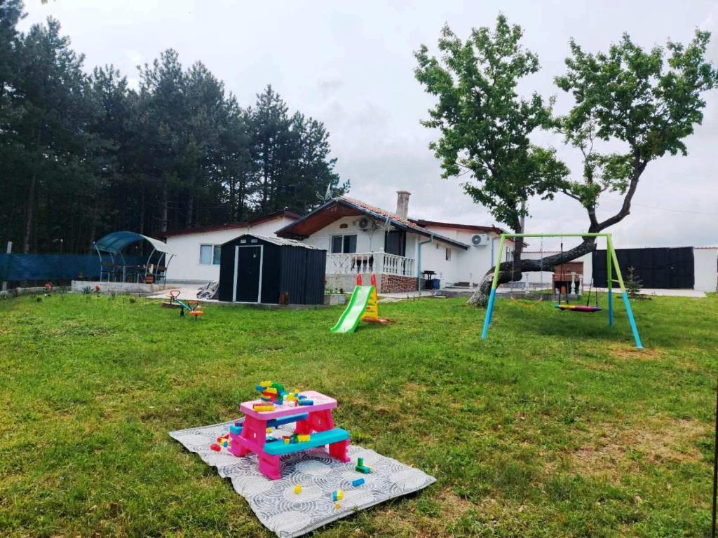 um quintal com um parque infantil com uma casa e uma árvore em Вила Мони-зона релакс 