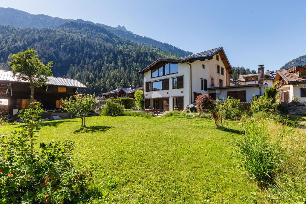 a large yard with a house and mountains in the background at Chalet Plein Centre - Savoyard Moderne - Happy Rentals in Chamonix
