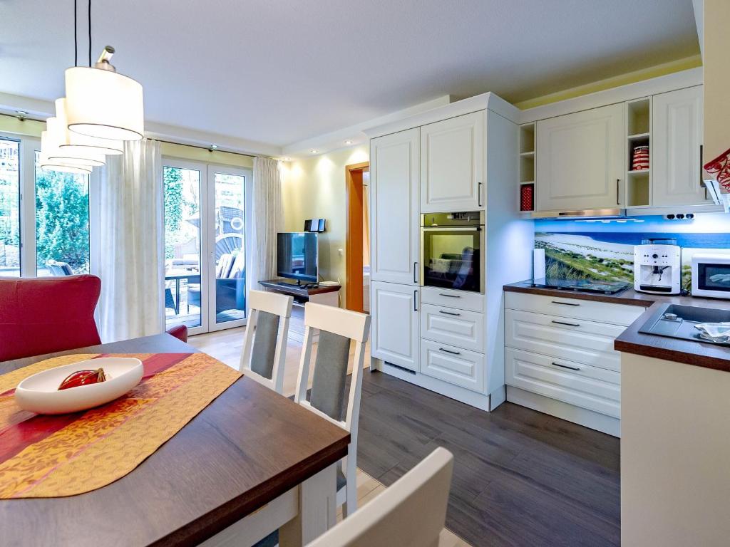 a kitchen with white cabinets and a table with a dining room at Residenz Margarete - Apt. 1.3 in Binz