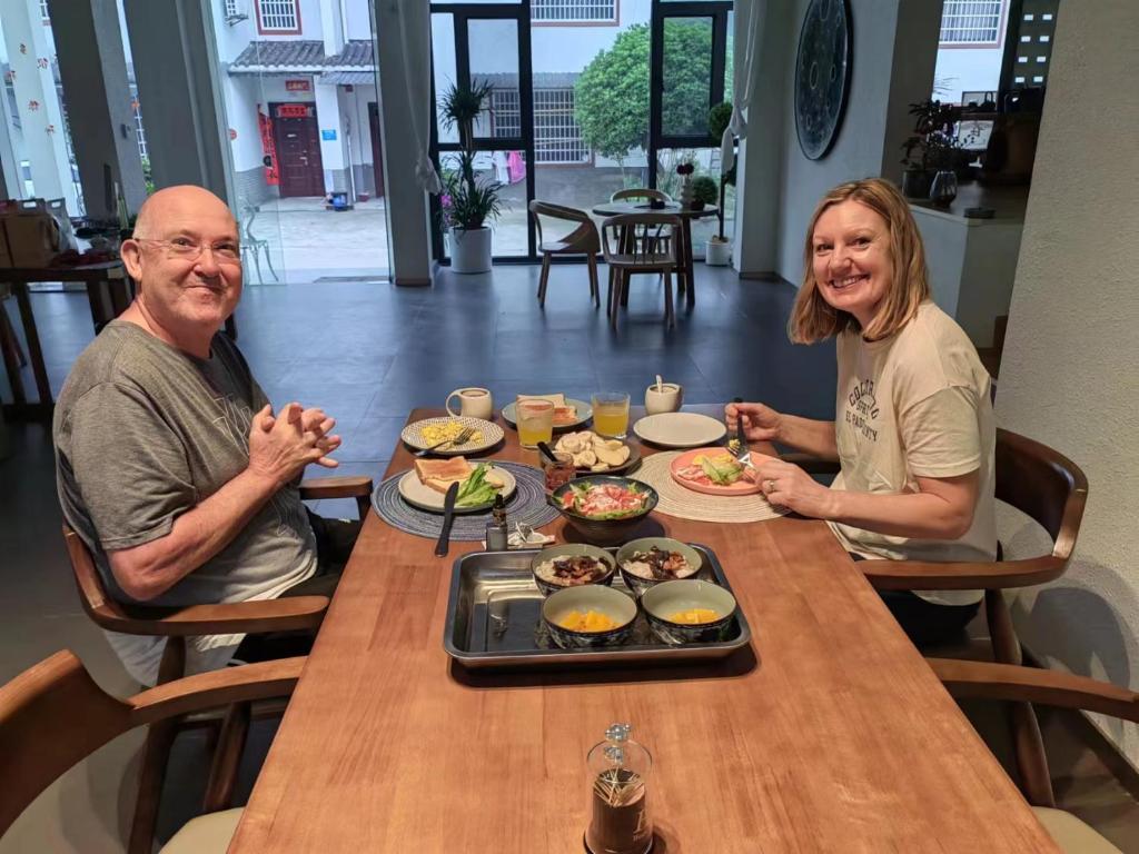a man and woman sitting at a table with food at Flower Whisperer Homestay Tianmenshan Store free airport and station pick-up in Zhangjiajie