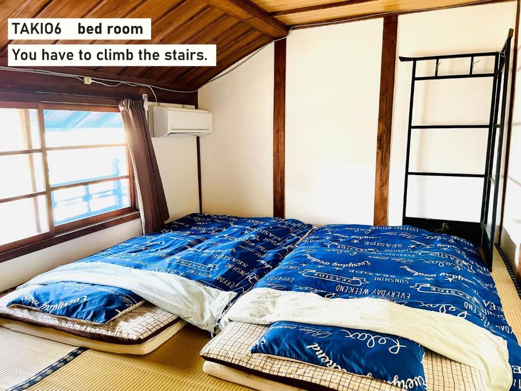 un letto con lenzuola blu in una stanza con finestra di TAKIO Guesthouse - Vacation STAY 12208v a Higashiosaka