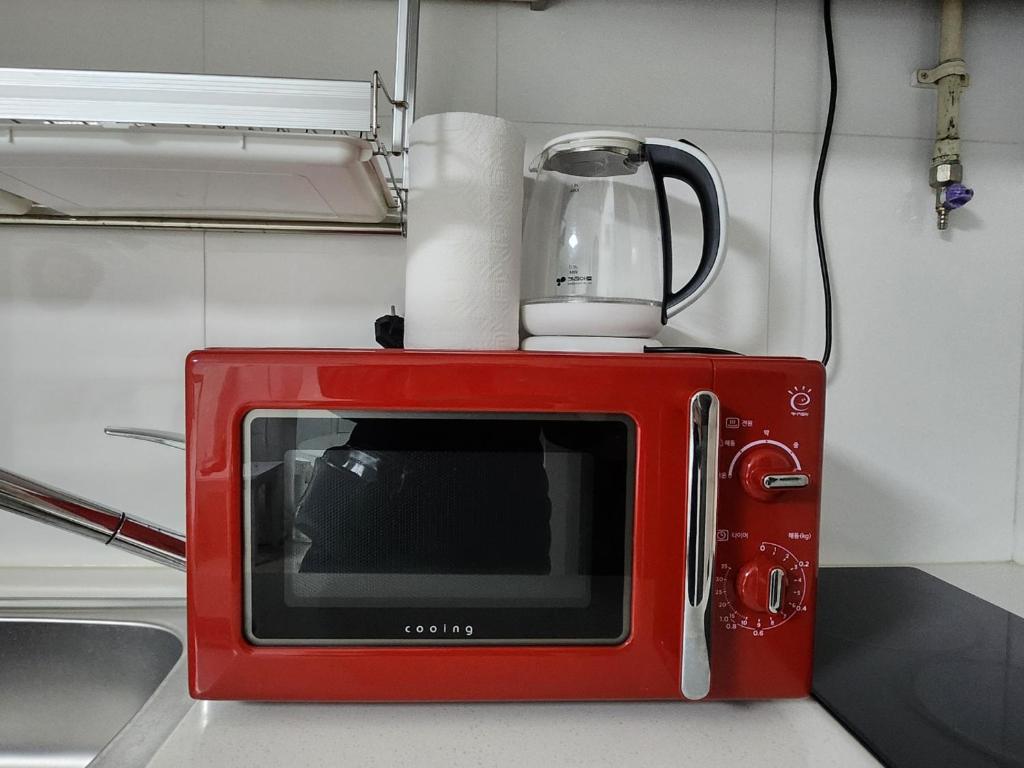 a red microwave sitting on top of a counter at Beautiful Sunset Jejubi House2 in Jeju