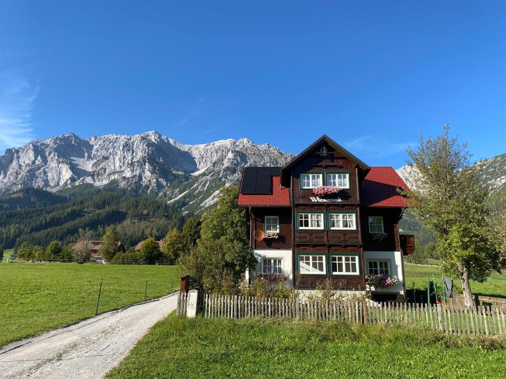 uma casa num campo com montanhas ao fundo em Appartements Wieseneck - beste Lage inklusive Sommercard em Ramsau am Dachstein