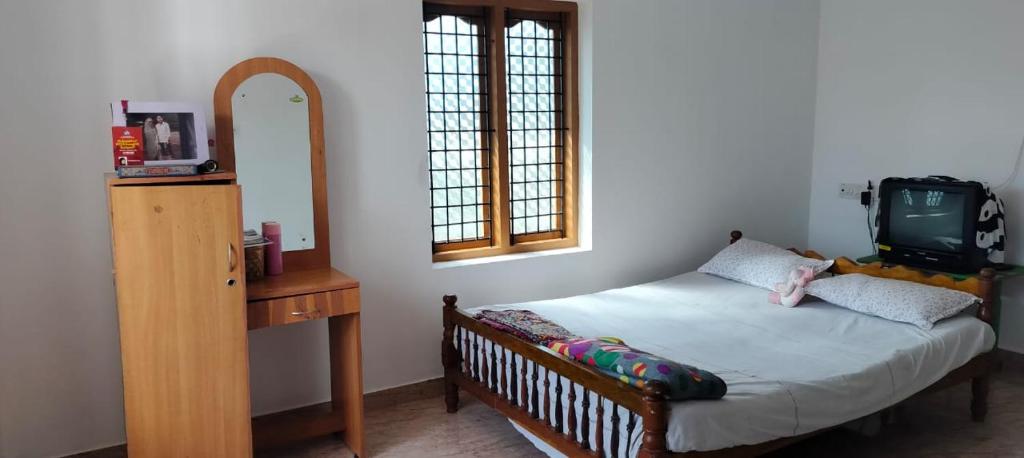 una camera con un letto e una piccola televisione di Bibgyor home stay a Bekal