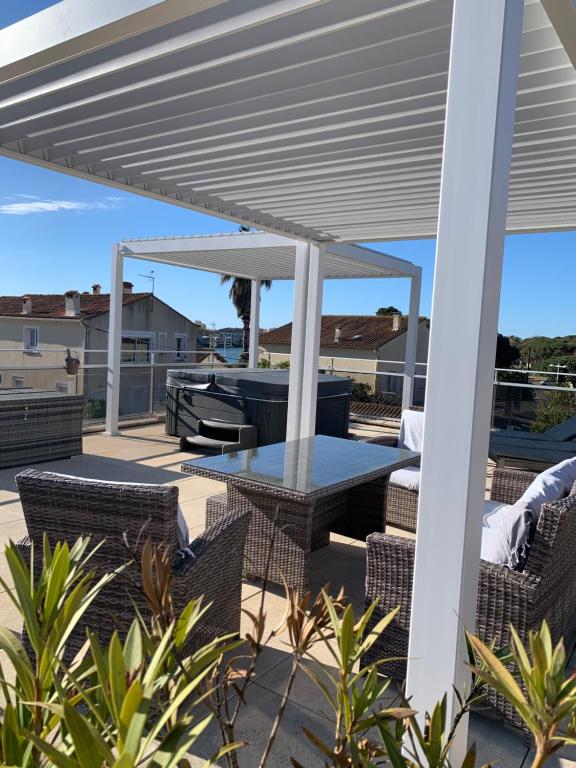 um pátio com uma mesa e cadeiras sob uma pérgola em Villa L'Amiraute em Agde