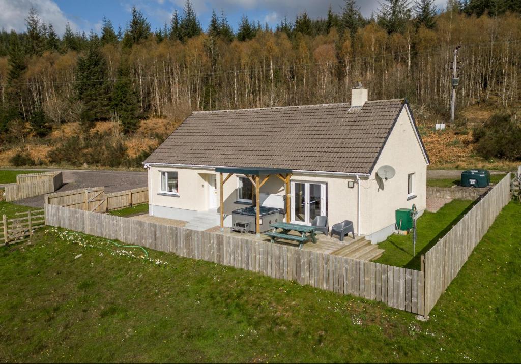 a small white house with a wooden deck at Loch Ness Cottage in Fort Augustus