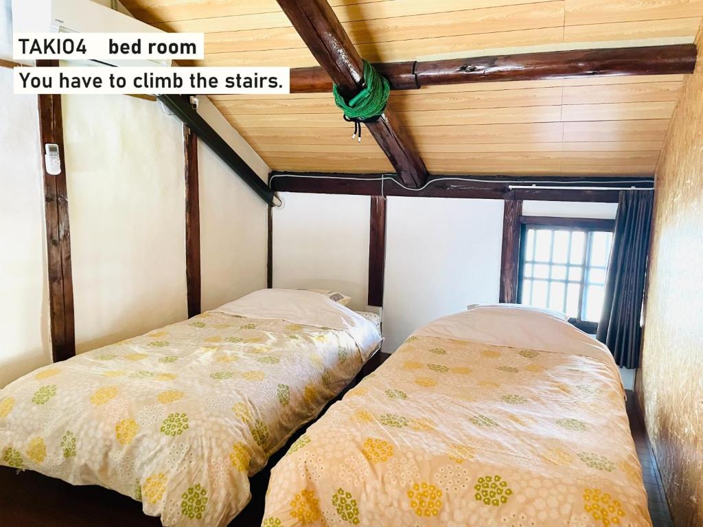 a bedroom with two beds and a wooden ceiling at TAKIO Guesthouse - Vacation STAY 12211v in Higashi-osaka