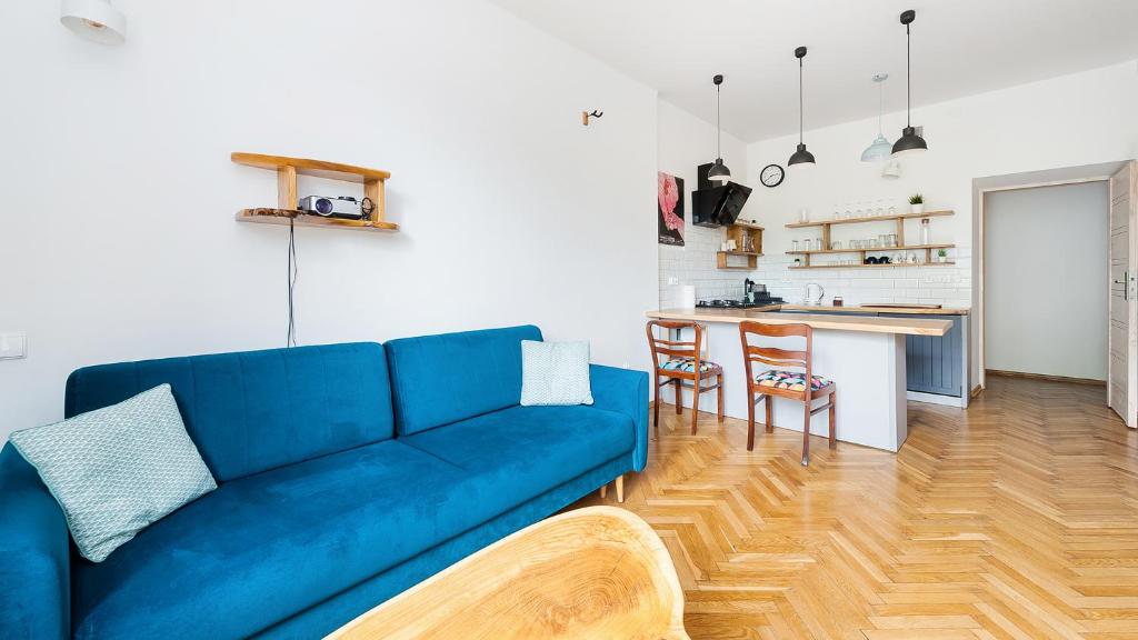 uma sala de estar com um sofá azul e uma cozinha em Apartamenty Sun & Snow Basztowa na Cracóvia