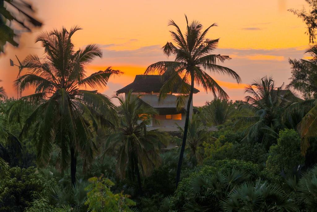 um edifício com palmeiras em frente a um pôr-do-sol em Pepo Villa, Anasa Hotels & Experiences em Lamu