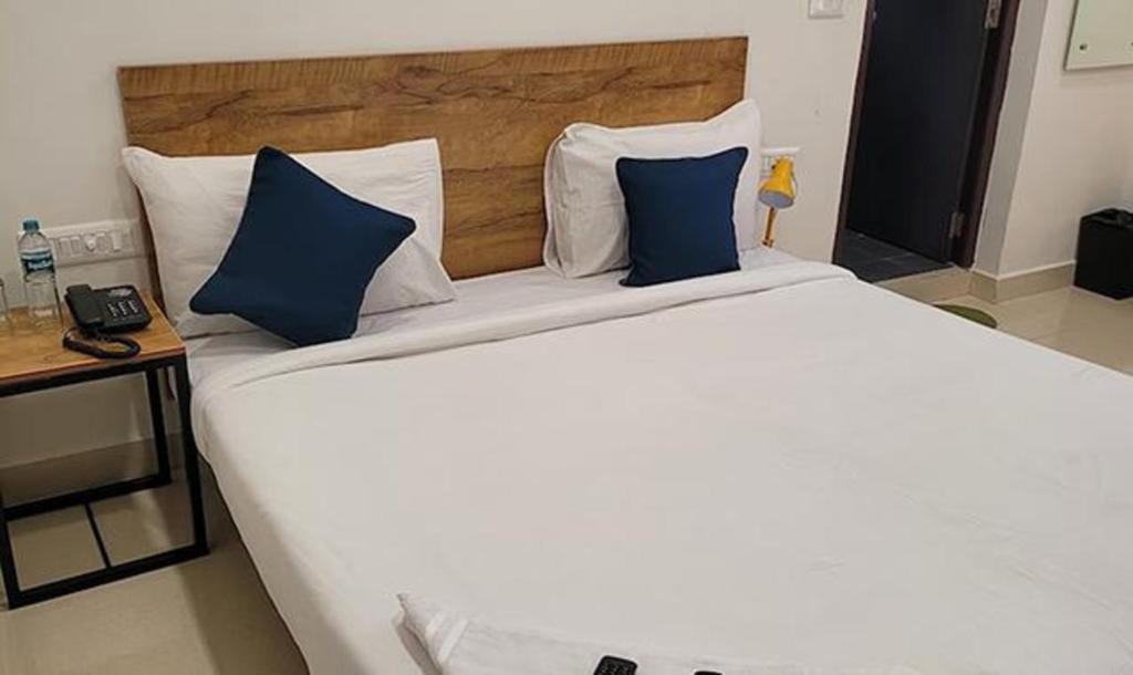 un grande letto bianco con cuscini blu in una stanza di FabHotel Rithik Heights Hitech City a Hyderabad